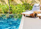 Thumbnail 1 of 10 - A pool with a chair and table by it.