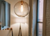 Thumbnail 5 of 5 - A table with a vase on it and a light bulb hanging from the ceiling.