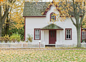 Thumbnail 1 of 5 - A white house with a red door and a green roof.