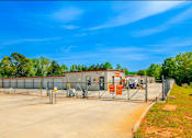 Thumbnail 3 of 6 - a fenced in area with a building in the background