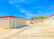Thumbnail 7 of 22 - a row of sheds in a parking lot with a blue sky