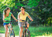Thumbnail 1 of 6 - a man and a woman riding bikes in the park