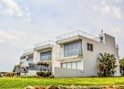 Thumbnail 4 of 5 - A modern house with a balcony and a flag on top.