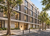 Thumbnail 1 of 6 - A modern building with a tree in front of it.
