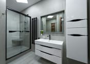 Thumbnail 10 of 10 - A modern bathroom with a white sink and a glass shower.