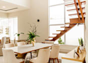 Thumbnail 1 of 2 - A dining room with a wooden table and white chairs.