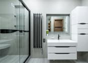 Thumbnail 3 of 10 - A modern bathroom with a white sink and a glass shower.