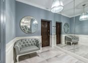 Thumbnail 3 of 10 - A grey tufted sofa sits in a hallway with a mirrored wall and a round mirror above it.