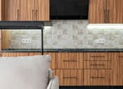 Thumbnail 5 of 21 - A modern kitchen with wooden cabinets and a black range hood.