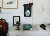 Thumbnail 3 of 8 - A white brick wall with a variety of objects including a globe, books, and framed pictures.