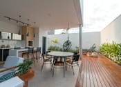 Thumbnail 1 of 8 - A modern outdoor dining area with a wooden floor and a white table.