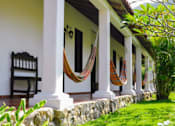 Thumbnail 6 of 9 - A porch with a bench and hammocks.