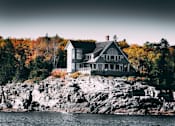 Thumbnail 12 of 14 - A house is built on a rocky outcrop by the water.