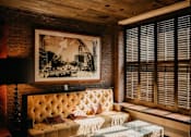 Thumbnail 4 of 5 - A room with a tufted sofa and a framed picture on the wall.