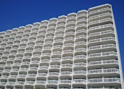 Thumbnail 5 of 5 - A tall white building with balconies on each floor.