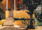 Thumbnail 2 of 5 - A yellow house with a tree in front.