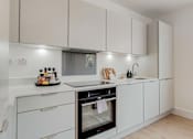 Thumbnail 1 of 7 - a kitchen with white cabinets and a stove and a sink