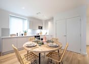 Thumbnail 5 of 6 - a kitchen and dining area with a table and chairs