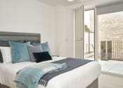 Thumbnail 11 of 29 - a bedroom with a large bed and a sliding glass door to a balcony