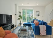Thumbnail 4 of 29 - a living room with a blue couch and a tv on the wall