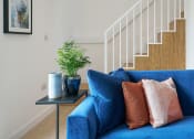 Thumbnail 5 of 29 - a living room with a blue couch and a small table with a plant on it