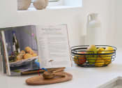 Thumbnail 7 of 29 - a cookbook sits on a counter next to a bowl of fruit