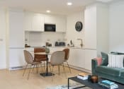 Thumbnail 19 of 29 - a living area with a small table with four chairs and a kitchenette in the background