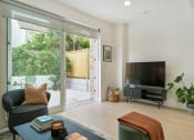 Thumbnail 18 of 29 - a living room with a tv and sliding glass doors to a garden