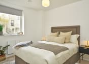 Thumbnail 21 of 29 - a bedroom with a bed and a nightstand