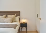 Thumbnail 22 of 29 - a bedroom with a bed and a nightstand with a lamp