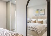 Thumbnail 29 of 38 - A bedroom with a large bed and a large mirror.