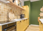Thumbnail 17 of 35 - A kitchen with yellow cabinets and a white countertop.