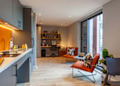 Thumbnail 28 of 36 - A modern kitchen with a dining area and a desk with a chair.