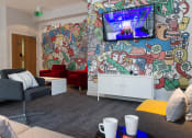 Thumbnail 2 of 16 - a living room with a mural on the wall and couches and a tv