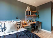 Thumbnail 23 of 36 - A bedroom with a bed, desk, and chair.