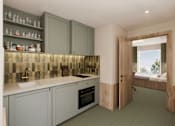 Thumbnail 24 of 26 - A kitchen with grey cabinets and a tiled backsplash.