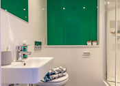Thumbnail 33 of 36 - A white sink and toilet in a bathroom with green glass.