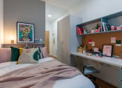 Thumbnail 20 of 35 - a bedroom with a bed and a desk with a work space