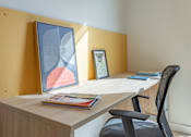 Thumbnail 31 of 35 - A desk with a chair and two picture frames on it.