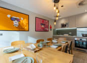 Thumbnail 6 of 15 - a dining room with a wooden table and a kitchen