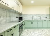 Thumbnail 24 of 25 - A kitchen with green cabinets and a marble backsplash.