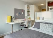Thumbnail 7 of 16 - a small bedroom with a desk and a bed