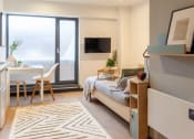 Thumbnail 9 of 19 - a bedroom with a bed and a desk and a sliding glass door