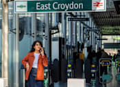 Thumbnail 52 of 54 - A woman is standing under a sign that says East Croydon.