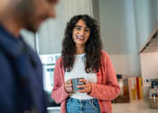 Thumbnail 11 of 54 - A woman in a pink cardigan is holding a mug with the word "Fresh" on it.