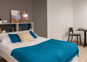 Thumbnail 11 of 21 - a bedroom with a bed and a desk with a chair