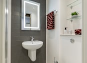 Thumbnail 35 of 35 - A white sink is mounted on a grey wall under a mirror.