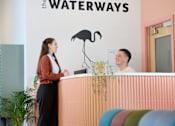 Thumbnail 26 of 35 - A woman is standing at the front desk of the Waterways.