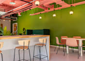 Thumbnail 21 of 36 - a restaurant with green walls and a bar with chairs and a table