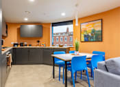 Thumbnail 5 of 35 - A kitchen with orange walls and a dining table with blue chairs.